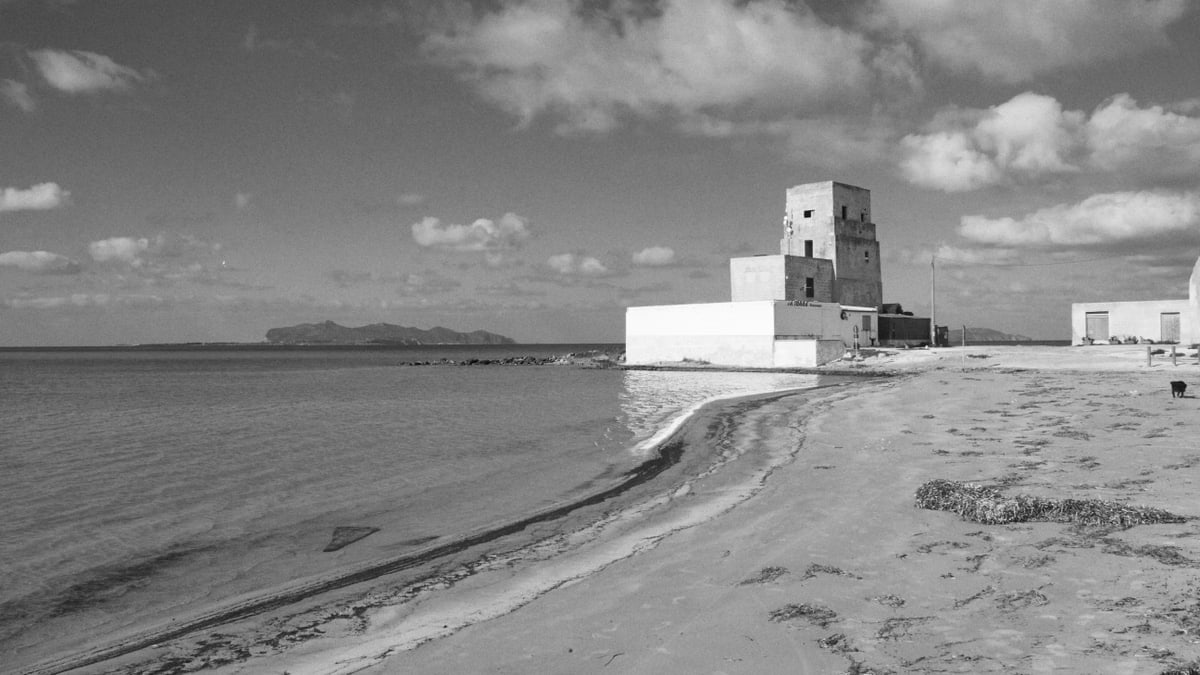 Black and white image of a historic beach tower in Trapani, Sicily with sweeping ocean views.